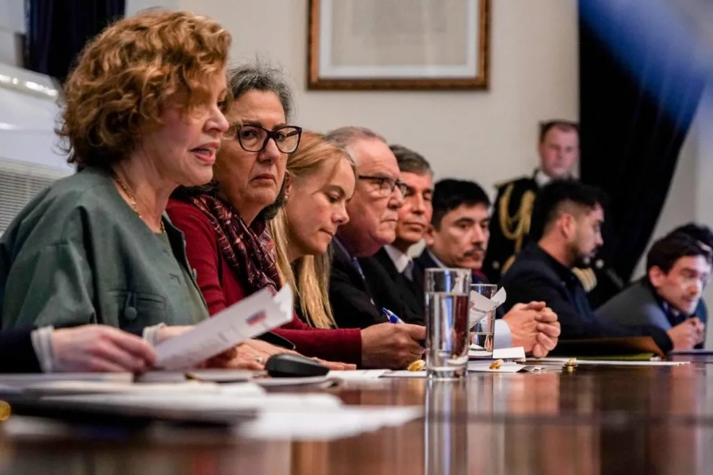 La ministra Catalina Parot lee un documento en la mesa del Consejo; a su lado, en fila, el resto de las autoridades asistentes a la sesión.