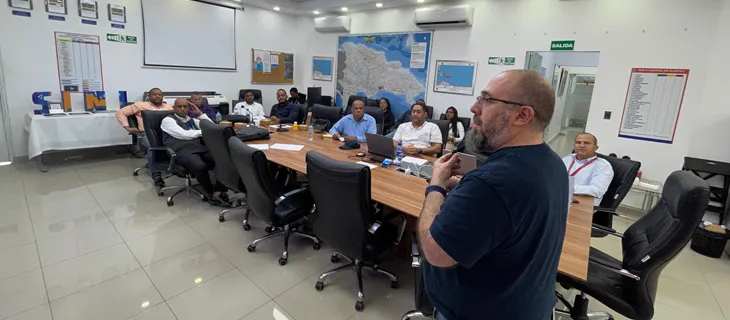 Taller en la sala de reuniones del SINI, con los participantes alrededor de una mesa alargada y el relator de pie explicando.