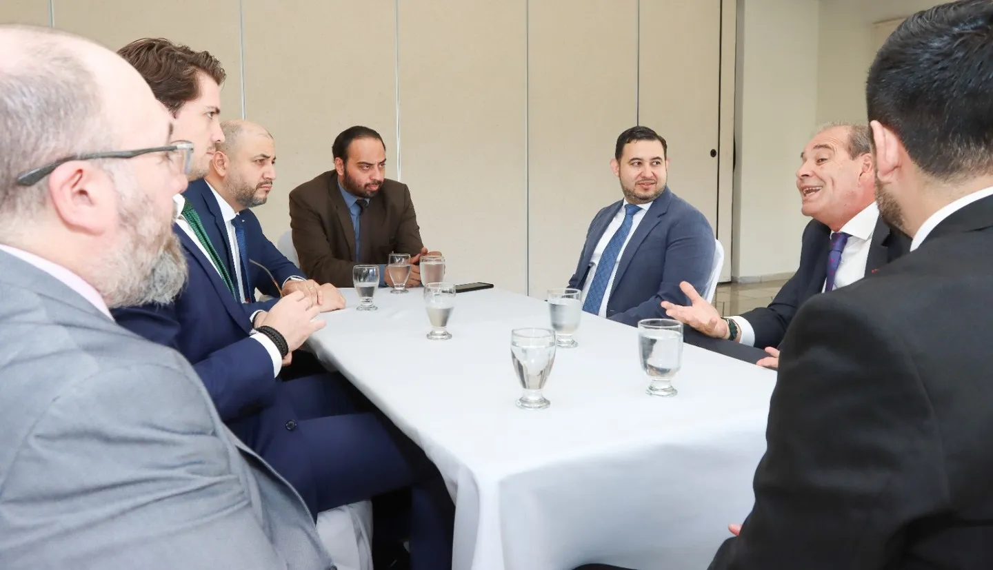 Las delegaciones de Chile y Honduras conversan en torno a una mesa; uno de los participantes gesticula mientras interviene.