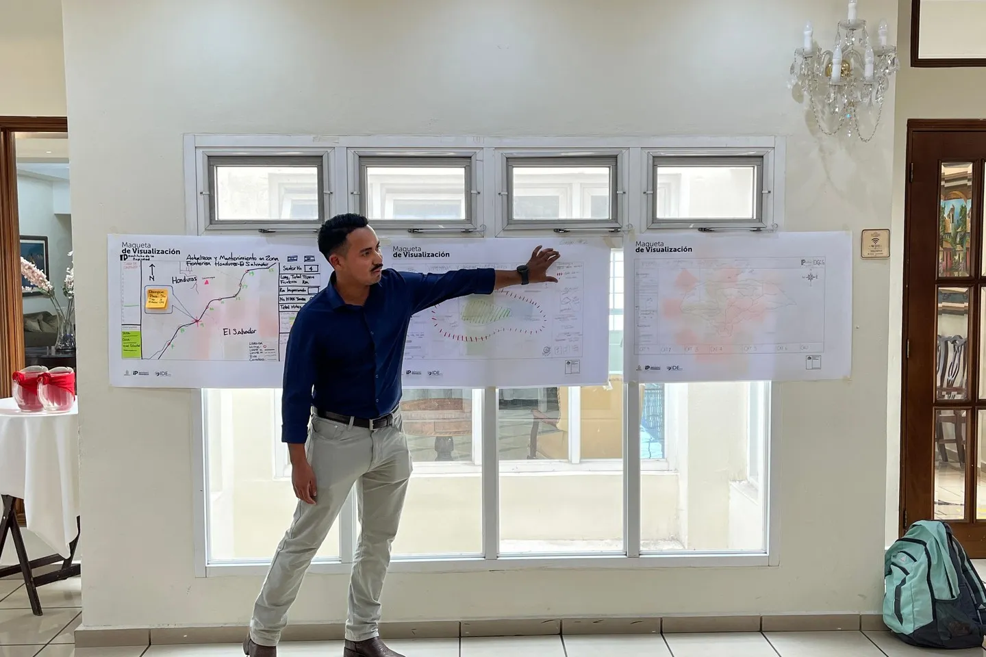 Un participante señala una de las tres maquetas de visualización dibujadas a mano y colgadas en la pared; la primera corresponde al mantenimiento de la zona fronteriza entre Honduras y El Salvador.