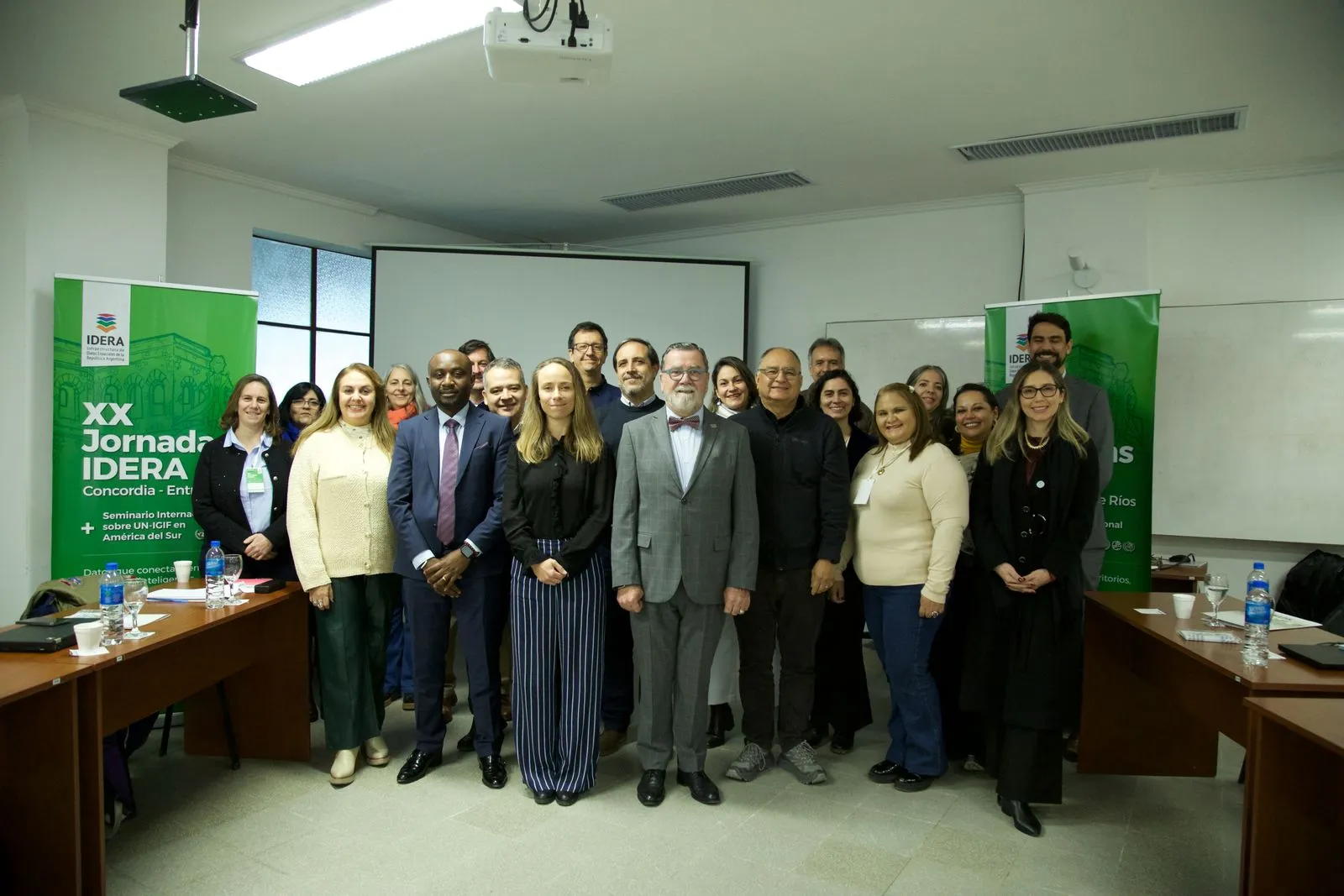 Fotografía grupal de una veintena de participantes entre dos pendones de las XX Jornadas IDERA y del seminario internacional sobre UN-IGIF en América del Sur.