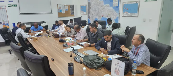 Los participantes trabajan alrededor de la mesa durante el módulo de modelos de datos, con mapas de la República Dominicana en la pared del fondo.